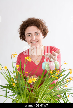 Junge lockig Frau hält, Ostereier und Eiern in gelben Narzissen aus Stockfoto