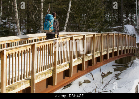 Wanderer auf der Rocky Gorge Bridge die Swift River in den White Mountains, New Hampshire USA während der Wintermonate durchquert Stockfoto