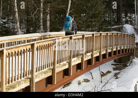 Wanderer auf der Rocky Gorge Bridge die Swift River in den White Mountains, New Hampshire USA während der Wintermonate durchquert Stockfoto