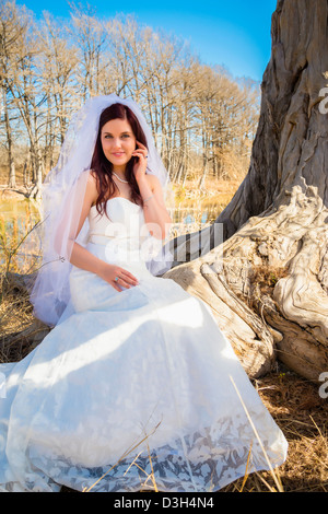 Kaukasische Braut im Hochzeitskleid sitzen in natürlicher Umgebung Stockfoto