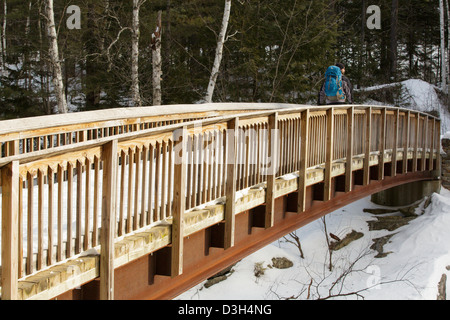 Wanderer auf der Rocky Gorge Bridge die Swift River in den White Mountains, New Hampshire USA während der Wintermonate durchquert Stockfoto