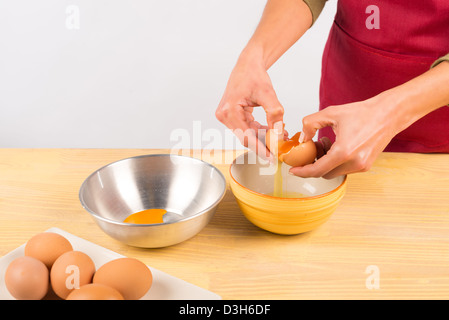 Weibliche Hände krachend und Ei und die weiße in eine Schüssel gießen Stockfoto