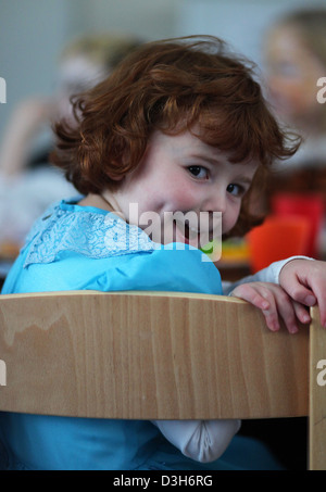 Porträt eines deutschen 4 jährige Mädchen sitzen mit anderen Kindern an einem Tisch im Kindergarten. Leipzig, Deutschland. Stockfoto