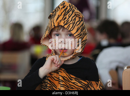 Ein deutscher fünfjähriger junge verkleidet als ein Tiger eine Saltstick zu essen, während eine Faschingsparty im Kindergarten. Leipzig, Deutschland Stockfoto
