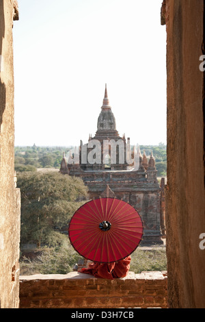 Junge Novize und Sonnenschirm, gerahmt in einem Torbogen Bagan-Tempel. Stockfoto