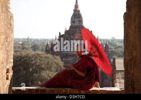 Junge Novize und Sonnenschirm, gerahmt in einem Torbogen Bagan-Tempel. Stockfoto