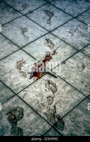 blutigen Fußspuren und ein Kruzifix in einer Blutlache auf einem Fußboden im Bad Stockfoto