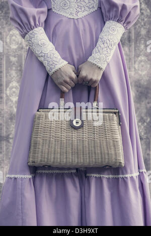 eine Frau in einem rosa Kleid mit einer Vintage Handtasche Stockfoto