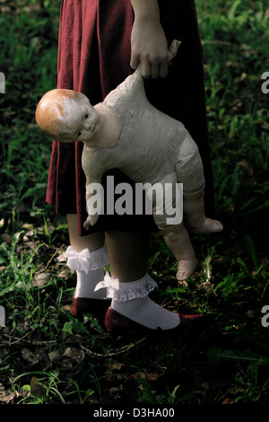 eine Frau in einem roten Kleid mit einer alten Puppe Stockfoto