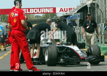 (Dpa) - Ferrari Team Mitglieder zusehen, wie Mechanik der McLaren-Mercedes Team Push-einem Rennwagen durch die Grube-Linie auf dem Albert Park Race track in Melbourne, Australien, 3. März 2004. Der Grand Prix von Australien startet der diesjährigen Formel 1-Saison am Sonntag auf der Rennstrecke Albert Park in Melbourne. Stockfoto