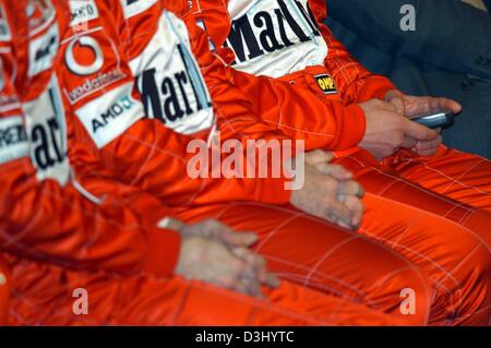 (Dpa) - deutsche Formel 1 pilot Michael Schumacher (R), sitzt neben brasilianischen Formel 1 pilot Rubens Barrichello (C) und Test Drvier Luca Badoer (L) und spielt mit seinem Handy bei der Enthüllung des Ferraris neue Formel ein Auto für die Saison 2004 in Maranello, Italien, 26. Januar 2004. Die Formel startet-1-Saison am 7. März in Australien. Stockfoto