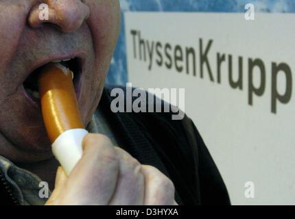 (Dpa) - ein Aktionär nimmt einen Bissen von einer Wurst vor dem Logo des Konzerns ThyssenKrupp Stahl steht während der Hauptversammlung in Bochum, Deutschland, 23. Januar 2004. ThyssenKrupp bestätigt ihr Ziel, ein Bruttoergebnis von knapp 1 Milliarde Euro im laufenden Geschäftsjahr 2003/2004 zu erreichen. Das Unternehmen kündigte auch die Eckdaten für das erste Quartal Stockfoto