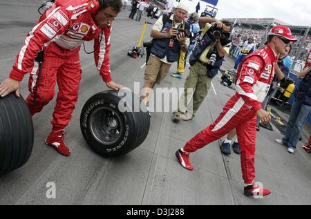 (Dpa) - das Bild zeigt deutsche Formel1 Fahrer Michael Schumacher (R) von Ferrari und ein Mechaniker mit Bridgestone-Reifen (L) vor dem Start zum Grand Prix in Indianapolis, USA, 19. Juni 2005. Der Grand Prix vorgestellten nur sechs Autos, weil alle sieben Teams, die mit Michelin-Reifen ausgestattet zog sich aus dem Rennen wegen Sicherheitsbedenken. Stockfoto