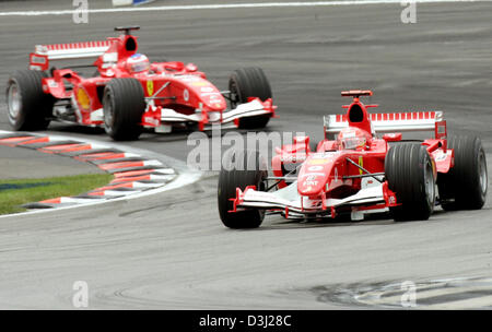 (Dpa) - das Bild zeigt deutsche Formel1 Fahrer Michael Schumacher (R) und seinem brasilianischen Teamkollegen Rubens Barrichello kurz nach dem Start des Grand Prix, das nur sechs Autos in Indianapolis, USA, Sonntag, 19. Juni 2005 kennzeichnete. Alle sieben Teams, die mit Michelin-Reifen ausgestattet zog sich aus dem Rennen aufgrund von Sicherheitsbedenken. Stockfoto