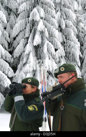 (Dpa) - Daisy Langer (L) und Dirk Bauer, Offiziere der Bundesrepublik Border Guards (BGS) beobachten die schneebedeckte Umgebung entlang der deutsch-tschechischen Grenze in Oberwiesenthal, Deutschland, 29. Januar 2004. 1.700 Offiziere bewachen einen 305 Kilometer langen Abschnitt der Grenze. Illegalen Eingang über die Grenze nach Deutschland stellt nach wie vor ein Problem dar. Stockfoto