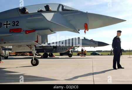 (Dpa-Dateien) - ein deutscher Soldat der Kämpfer-Geschwader 73 Steinhoff steht vor einem Eurofighter (vorne), gesetzt, um der russischen MIG-29 Kämpfer (zurück) ersetzen auf dem Luftwaffenstützpunkt in Laage, Deutschland, 26. September 2003. Medienberichten zufolge schneidet der deutsche Verteidigungsminister das Militärbudget von 25 auf 26 Milliarden Euro. Der Minister sieht eine Rekonstruktion der Germa Stockfoto