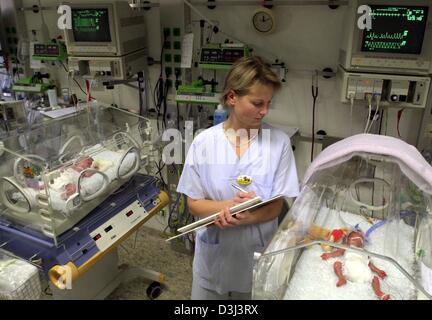 (Dpa) - Kinderkrankenschwester Birgit Herlemann prüft auf die Vitalfunktionen des kleinen Mädchens Pauline, die in einem Inkubator in der pädiatrischen Klinik des Unversity Hospital in Greifswald, Deutschland, 13. November 2003 liegt. Pauline wurde in der 26. Woche der Schwangerschaft, geboren mit einem Gewicht von nur 820 Gramm. Neonatologie ist ein Grenzgebiet der Medizin ständig navigieren zwischen Leben und Tod, Gesundheit und Stockfoto