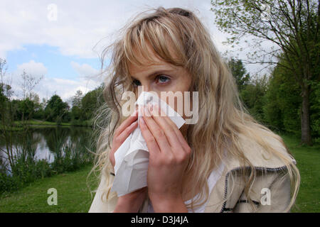 (Dpa-Datei) - das Bild vom 6. Mai 2005, zeigt eine junge Frau bläst ihre Nase mit einem Papiertaschentuch in Gescher, Deutschland.  Im Freien wird oft ein Aufwand für einen Allergiker. Pollen fliegen reizt die Schleimhäute und wilde niesende Angriffen provozieren kann. Stockfoto