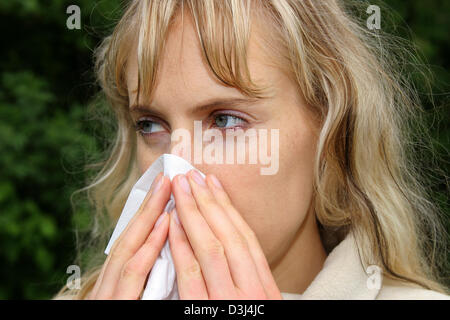 (Dpa-Datei) - das Bild vom 6. Mai 2005, zeigt eine junge Frau bläst ihre Nase mit einem Papiertaschentuch in Gescher, Deutschland.  Im Freien wird oft ein Aufwand für einen Allergiker. Pollen fliegen reizt die Schleimhäute und wilde niesende Angriffen provozieren kann. Stockfoto