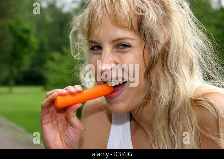 (Dpa-Datei) - das Bild vom 6. Mai 2005, zeigt eine junge Frau essen eine Karotte in Gescher, Deutschland. Stockfoto