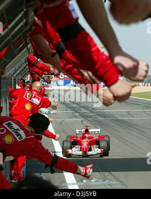 (Dpa) - deutsche Formel 1-Weltmeister Michael Schumacher (Ferrari) vorbei an seinem Mechaniker-Team fährt nach dem Gewinn der Europäischen Grand Prix auf dem Nürburgring-Rennen verfolgen in Deutschland, 30. Mai 2004. Stockfoto