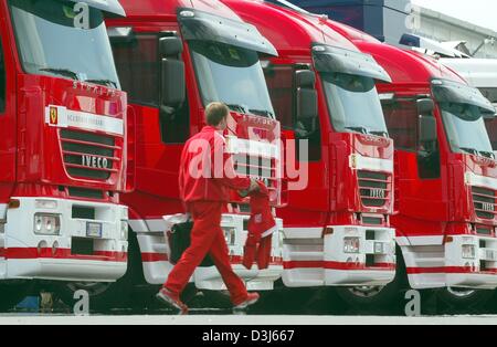 (Dpa) - Spaziergänge vorbei an einer Reihe von LKW im Fahrerlager am Nürburgring, Deutschland, 27. Mai 2004 ein Ferrari-Techniker. Am Wochenende wird der Grand Prix von Europa an der berühmten Rennstrecke stattfinden. Stockfoto