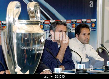 (Dpa) - Jose Mourinho (L), Cheftrainer der portugiesische Fußballverein FC Porto und seine Spieler Secretario (R) sitzen in der Nähe der Champions-League-Trophäe während einer Pressekonferenz in Gelsenkirchen, Deutschland, Dienstag, 25. Mai 2004. Das Team des ehemaligen französischen World Cup champ Didier Deschamps, AS Monaco, Portugiesen FC Porto im Finale der Champions League am Mittwoch, 26. Mai um zusammenkommen Stockfoto