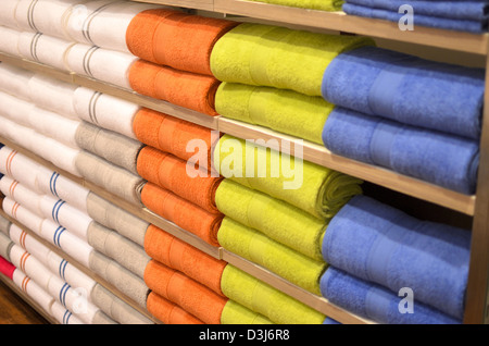 haufenweise bunte Handtücher in den Regalen Stockfoto