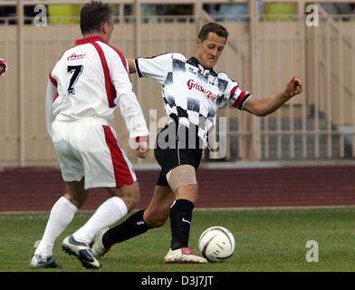 (Dpa) - MIAS deutscher Formel-1-Weltmeister Michael Schumacher (R) für den Ball mit Didier Deschamps, der Trainer des AS Monaco Fußballclub, während ein Benefiz-Fußballspiel in Monaco, 18. Mai 2004. Eine Gruppe von Formel-1-Rennfahrer spielten gegen eine Mannschaft, angeführt von Prinz Albert von Monaco. Stockfoto