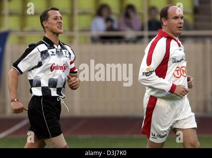 (Dpa) - deutscher Formel-1-Fahrer Michael Schumacher (L) und Prinz Albert von Monaco Joggen auf dem Feld während ein Benefiz-Fußballspiel in Monaco, 18. Mai 2004. Eine Gruppe von Formel-1-Rennfahrer spielten gegen eine Mannschaft, angeführt von Prinz Albert von Monaco. Prinz Albert-Team gewann das Spiel 4: 3. Formel 1 Grand Prix von Monaco wird am Sonntag, 23. Mai 2004 stattfinden. Stockfoto