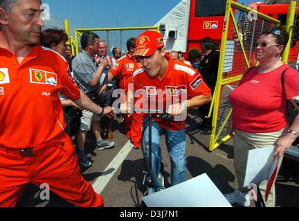 (Dpa) - fährt deutsche Formel 1-Weltmeister Michael Schumacher (C) durch die neue Boxengasse auf dem Stadtkurs auf seinem Kickboard in Monaco 19. Mai 2004. Die Formel 1 Grand Prix von Monaco wird am Sonntag, 23. Mai 2004 stattfinden. Stockfoto