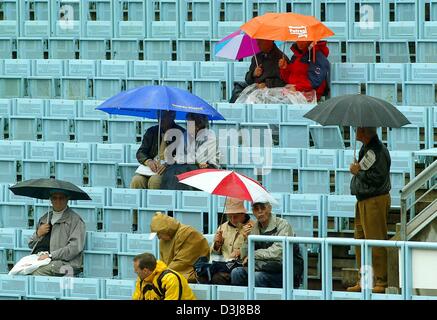 (Dpa) - Tennis-Fans mit Sonnenschirmen warten die Viertel-Finale der German Open auf dem Center Court in Berlin, 7. Mai 2004 beginnen. Stockfoto