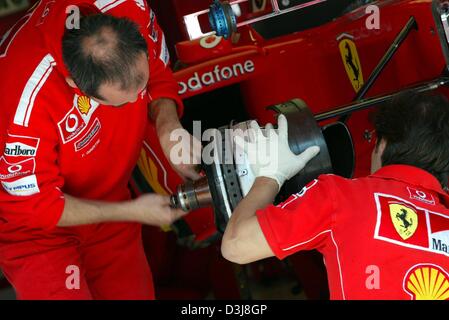 (Dpa) - Ferrari-Mechaniker auf die Bremsen der Rennwagen der Formel 1-Weltmeister Michael Schumacher auf dem Circuit de Catalunya Formel 1 Rennen verfolgen in der Nähe von Barcelona, Spanien, 6. Mai 2004 arbeiten. 9. Mai 2004 werden im Gange den Formel 1 Grand Prix von Spanien. Stockfoto