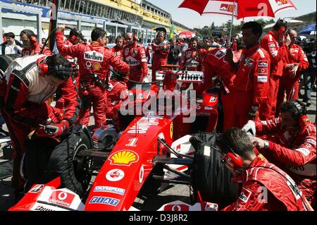 (Dpa) - letzte Vorbereitungen werden gemacht von seinem Team als deutscher Formel-1 pilot Michael Schumacher erwartet zum Jahresbeginn 2004 San Marino Grand Prix in Imola, Italien, 25. April 2004. Schumacher (Ferrari-Team) würde fortfahren, um das Rennen zu gewinnen. Stockfoto