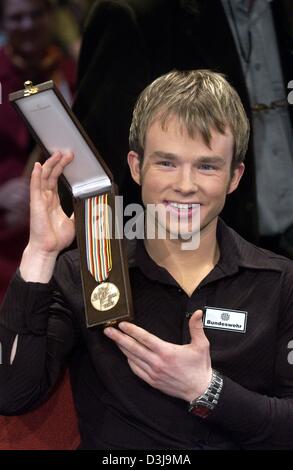 (Dpa) - deutscher Eiskunstläufer Stefan Lindemann zeigt seine kürzlich gewonnene Bronzemedaille während einer Talkshow in Leipzig, Deutschland, 2. April 2004. Lindemann hatte sensationell die Goldmedaille bei den Eiskunstlauf-Weltmeisterschaften in Dortmund, Deutschland, am Ende des März gewonnen. Es ist der größte Erfolg für einen männlichen Eiskunstläufer aus Deutschland in 21 Jahren. Stockfoto