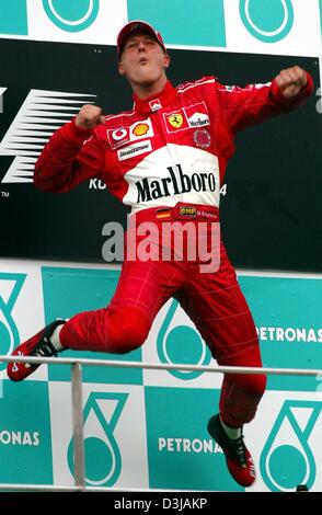 (Dpa) Der deutsche Formel 1-Weltmeister Michael Schumacher (Ferrari) springt in Freude nach dem Sieg der Grand Prix von Malaysia auf dem Sepang Rennstrecke in der Nähe von Kuala Lumpur auf Montag, 22. März 2004. Schumacher gewann seinen zweiten Sieg im zweiten Rennen der Saison mit einem unverwundbar Start Ziel Sieg. Stockfoto