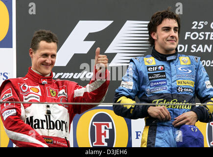 (Dpa) - spanische Formel 1-Fahrer Fernando Alonso (L) von Renault und Sekunde platziert deutsche Michael Schumacher Ferrari, der ein Daumen hoch, Lächeln gibt, wie sie auf dem Podium stehen, nachdem Alonso den Grand Prix von San Marino in Imola, Italien, 24. April 2005 gewann. Stockfoto