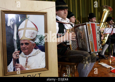 (Dpa) - eine traditionelle bayerische Blasmusik spielt auf der Bühne neben einem Bild (L) von der neugewählte Papst Benedikt XVI. in Marktl am Inn, Deutschland, 19. April 2005. Kardinal Joseph Ratzinger, geboren in Marktl am Inn, neue Papst Benedikt XVI., der erste deutsche Papst in den letzten 480 Jahren gewählt wurde. Stockfoto