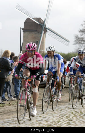 (Dpa) - deutsche Radfahrer Steffen Wesemann (L) und eine Gruppe von anderen Radfahrern fahren vor einer Windmühle über Kopfsteinpflaster während des traditionellen Paris-Roubaix-Rennens in der Nähe von Compiègne, Frankreich, 10. April 2005. Wesenmann war der beste deutsche Fahrer mit Position 16. Ca. 55 Kilometer von der berühmten 259 Kilometer langen Rennen nehmen die Fahrer über die berühmt-berüchtigten Kopfsteinpflaster-Straßen des nördlichen Fran Stockfoto