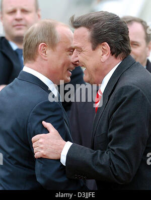 (Dpa) - lächelt German Chancellor Gerhard Schroeder (R), als er russische Präsident Wladimir Putin (L) am Flughafen in Hannover, Deutschland, 10. April 2005 begrüßt. Schröder und Putin eröffnet das weltweit größte Inustrial Messe an diesem Abend in Hannover. Stockfoto