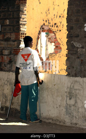 Ein Opfer von Landminen auf Krücken steht in einem Haus gegenüber einer Granate Loch in der völlig zerstörten Stadt Kuito, Angola, etwa zwei Stunden mit dem Flugzeug aus der Hauptstadt Luanda. Foto aufgenommen am 3. September 2003. In die zehn Jahren bis ein Waffenstillstand erreicht war schwere Kämpfe in und um Kuito getötet, rund ein Drittel der 500.000 Einwohnern. Noch die Umgebung von Kui Stockfoto