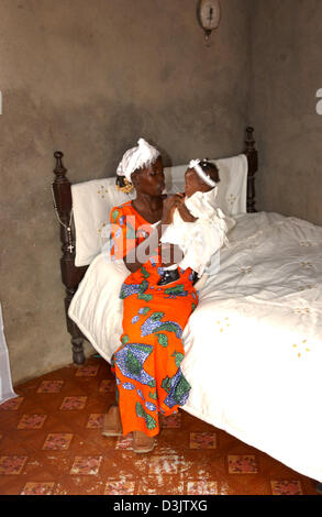(Dpa) - sitzt auf ihrem Bett in ihrem Haus wurde für 900 Dollar gebaut und besteht aus einem Zimmer im Quartier Kilauba Kiaxi ist eines der besseren Viertel in der Hauptstadt Luanda, Angola, 1. September 2004 Elma Manuel mit ihrer fünf Monate alten Tochter Paula. Stockfoto