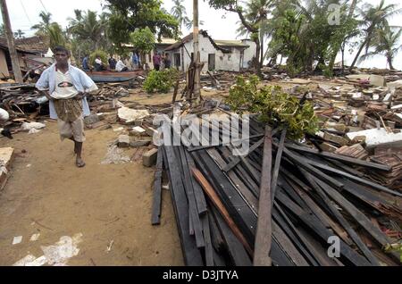 (Dpa) - geht ein Mann durch Schutt und Geröll in der zerstörten Stadt von Wadduwa, Sri Lanka, 28. Dezember 2004. Die Küste von Sri Lanka war eines der Gebiete, die von dem verheerenden Tsunami, der bis heute den Tod von mehr als 150.000 Menschen in Südasien entstanden am stärksten betroffen. Es ist immer noch eine Bedrohung von Volkskrankheiten durch zerstörte Sanitäranlagen und erfüllter Leichen. Stockfoto