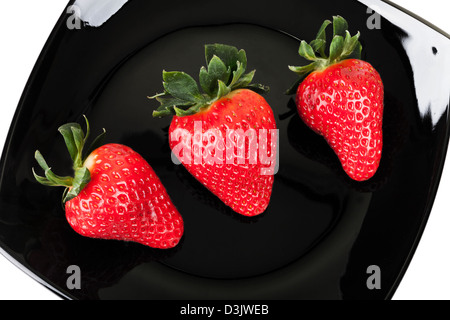 Drei frische Erdbeeren auf schwarz Untertasse, Ansicht von oben Stockfoto