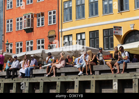 Kopenhagen, Dänemark, sitzen Touristen auf dem Steg am Nyhavn Stockfoto