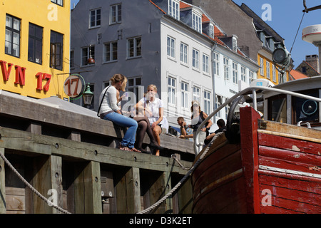 Kopenhagen, Dänemark, sitzen Touristen auf dem Steg am Nyhavn Stockfoto