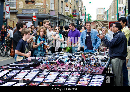 Familie Feilschen um Sonnenbrillen mit Markt-Stall-Inhaber auf der Brick Lane Stockfoto