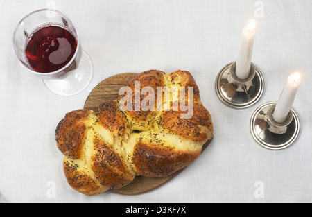 Shabbat Mahlzeit des Challah, Glas Wein, mit zwei Kerzen im Kerzen angezündet. Stockfoto