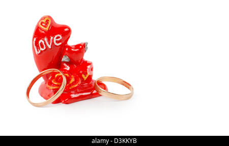 Zwei goldene Ringe mit Zeichen der Liebe in Form oder einem roten Ornament eingeschrieben mit dem Wort Liebe Stockfoto