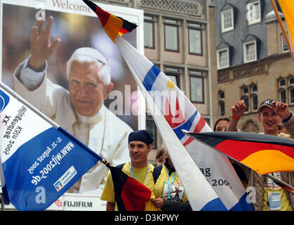 (Dpa) - Lächeln Pilger von der deutschen Stadt Geilenkirchen, wie sie mit ihren Fahnen ein großes Plakat von Papst Benedict XVI in Köln, Deutschland, 16. August 2005 passieren. Bis zu 1 Million Pilger aus der ganzen Welt werden erwartet den 20. Weltjugendtag vom 16. August bis 21. August 2005. Foto: Oliver Berg Stockfoto